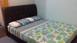 A bed with a floral bedspread, a dark headboard, and striped pillows. - Iqra Damai Inn (Bachok)