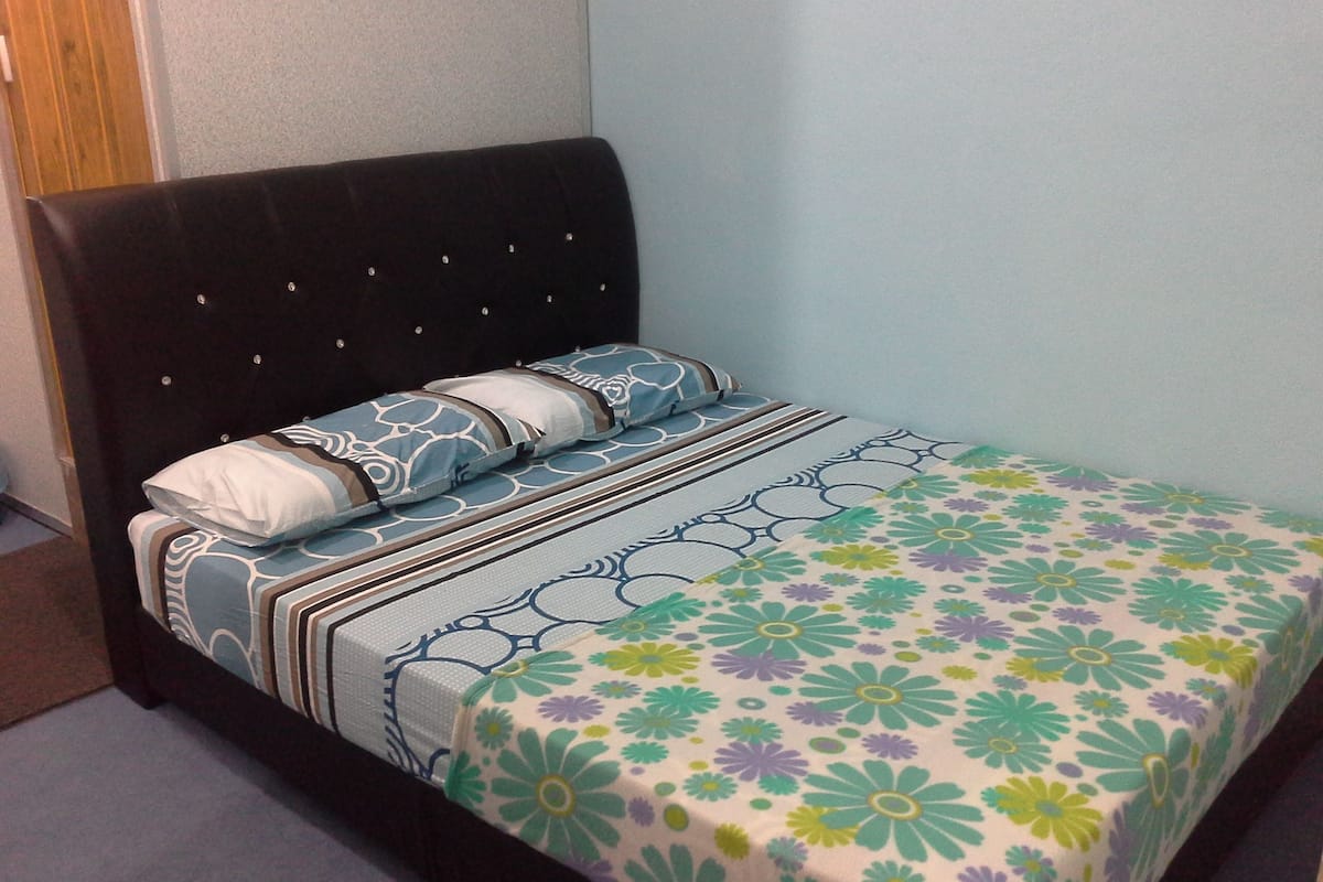A bed with a floral bedspread, a dark headboard, and striped pillows.