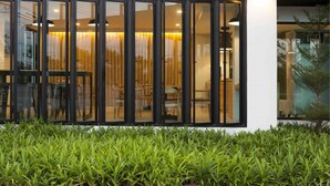 A modern building with large glass windows, a white exterior, and a well-maintained green lawn in front. - Easy Hotel (Lamphun)