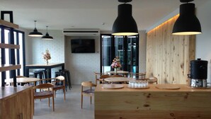 A modern kitchen with wooden countertops, black pendant lights, and a central island with a coffee machine. - Easy Hotel (Lamphun)