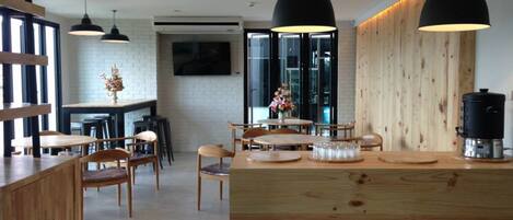 A modern kitchen with wooden countertops, black pendant lights, and a central island with a coffee machine.