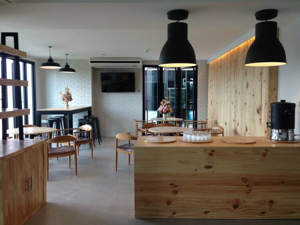 A modern kitchen with wooden countertops, black pendant lights, and a central island with a coffee machine. - Easy Hotel (Lamphun)
