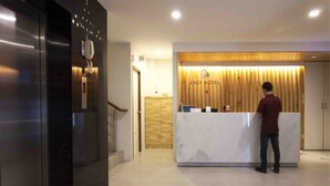 A reception desk with a wooden backdrop and a marble counter. - Easy Hotel (Lamphun)