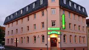Un hotel con un cartel llamativo que dice 'W HOTEL', un restaurante 'WEBERHOF' y un cartel que indica 'HOTEL' en la esquina.