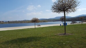 Un parque junto al lago con un banco, árboles y equipo de ejercicio.