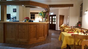 Un restaurante con muebles de madera, una barra y arreglos florales.