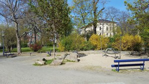 Un parque con bancos, un área de juegos y un edificio al fondo.