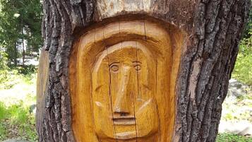 Una escultura de madera tallada en el tronco de un árbol, rodeada de losas de piedra.