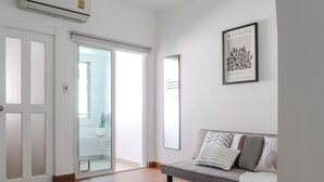 A modern living room with a grey sofa, a fluffy rug, and a framed artwork on the wall. - Link Mansion (Chiang Mai)