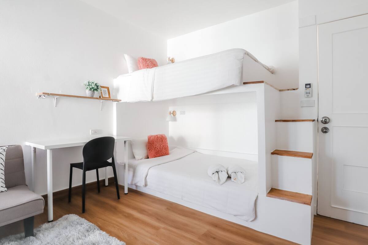 A compact, modern room with a bunk bed, a desk, and a chair.
