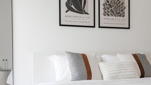 A hotel room with a large bed, white bedding, a wooden floor, and two framed artworks on the wall. - Link Mansion (Chiang Mai)