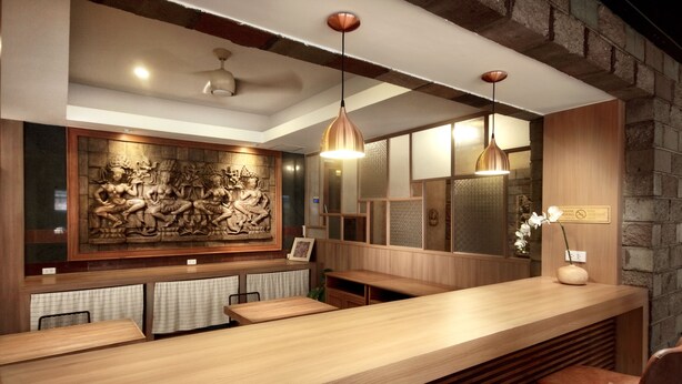 A modern bar area with a wooden counter, seating, and a decorative wall with a relief sculpture. - Link Mansion (Chiang Mai)