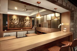 A modern bar area with a wooden counter, seating, and a decorative wall with a relief sculpture. - Link Mansion (Chiang Mai)