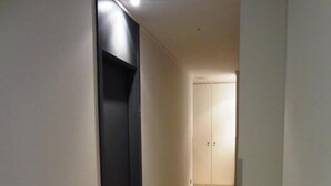 A hallway with a black elevator, a white door at the end, and a tiled floor. - Hotel Irixo (Ourense)