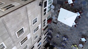 An aerial view of a building with multiple floors, large windows, and outdoor seating areas with tables and chairs. - Hotel Irixo (Ourense)