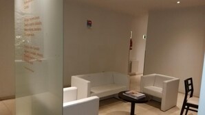 A modern, minimalist room with a white sofa, two armchairs, and a small table. - Hotel Irixo (Ourense)