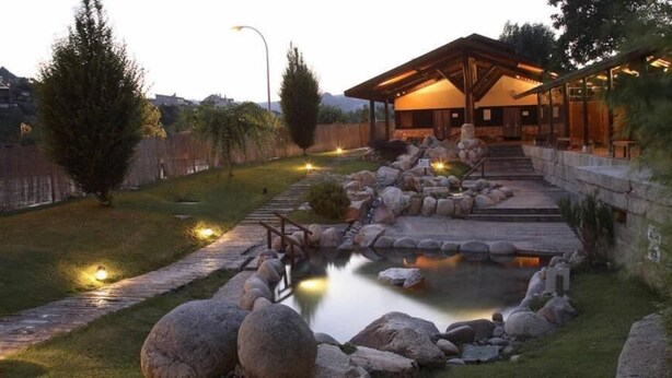 A serene garden with a pond, stone pathway, and a wooden building with a covered patio area. - Hotel Irixo (Ourense)