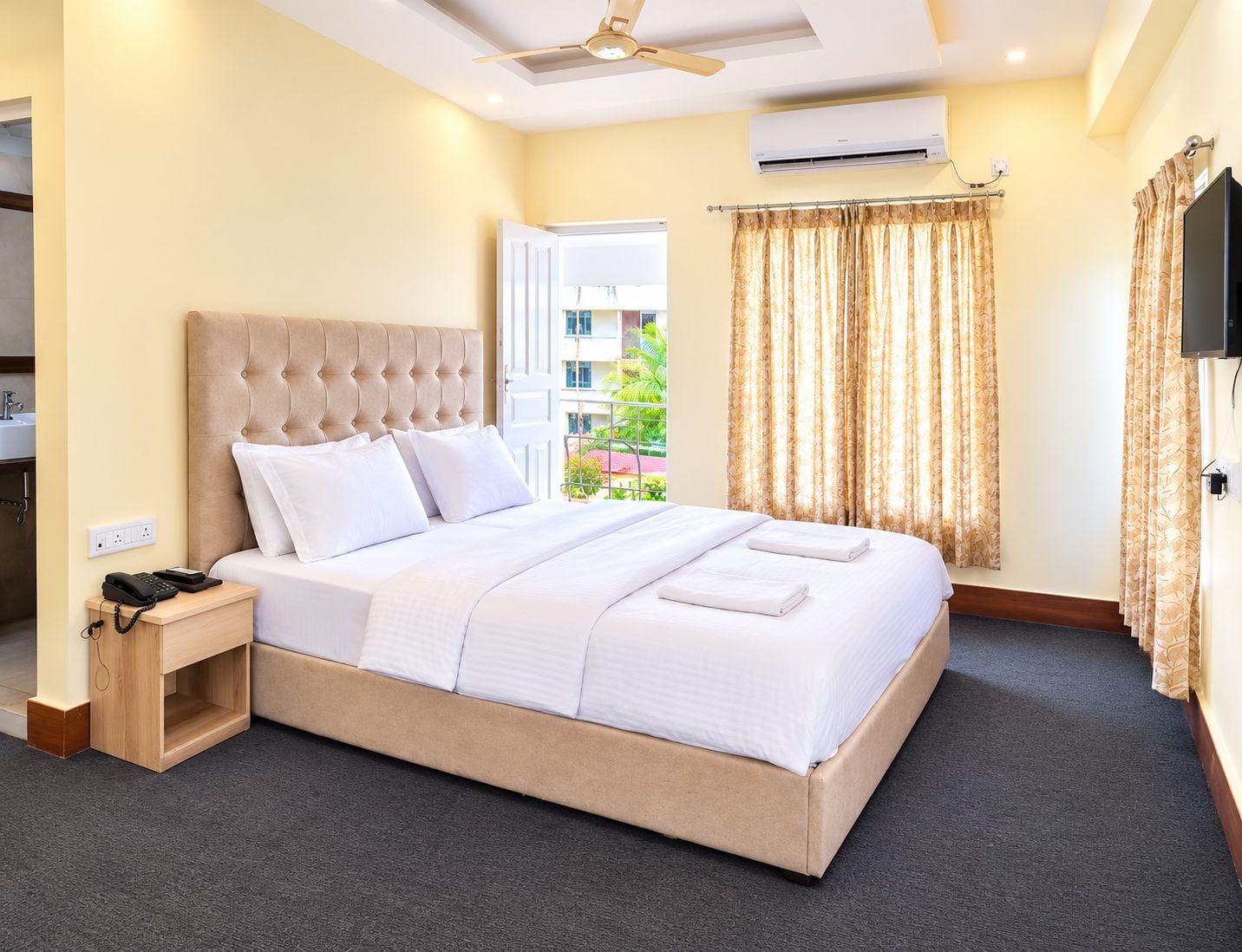 Habitación de hotel con cama, mesita de noche y vistas al exterior.