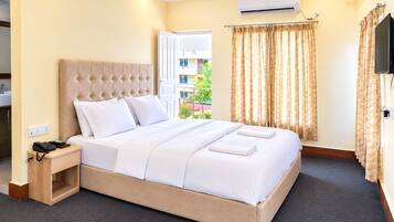 Habitación de hotel con cama, mesita de noche y vistas al exterior.
