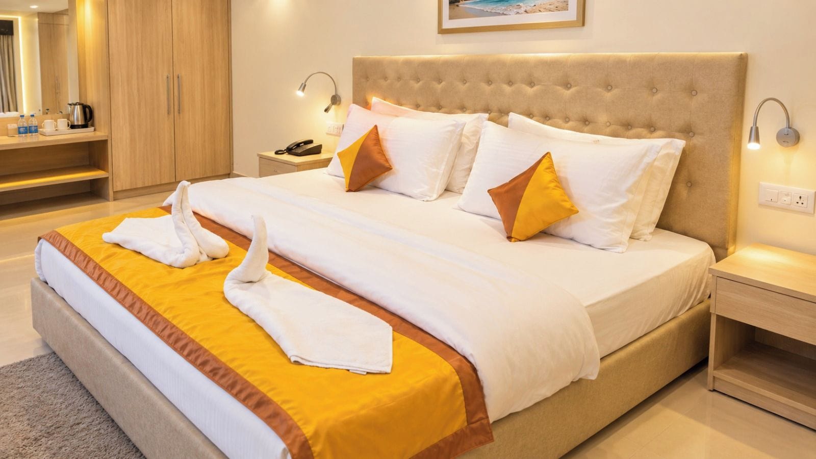 A hotel room with a large bed, a bedside table, a nightstand, a lamp, and a wall-mounted picture.