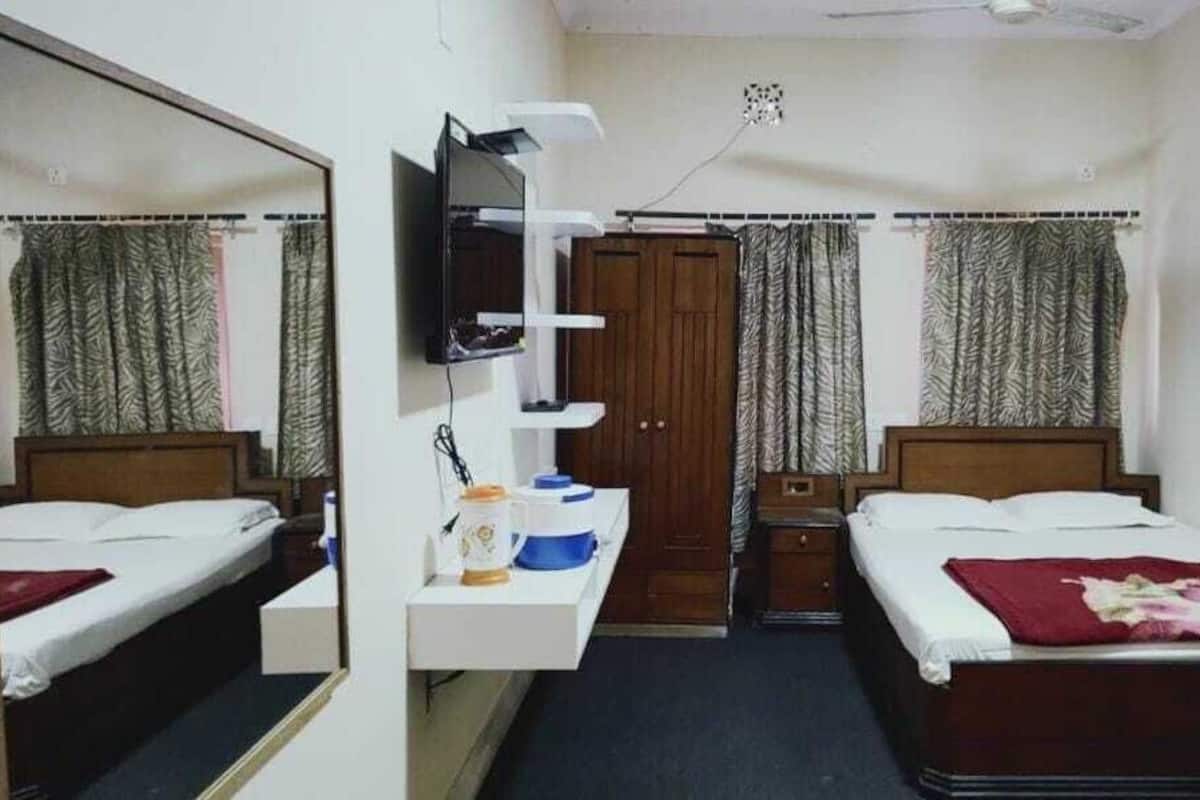 Ein Schlafzimmer mit zwei Betten, einem Schreibtisch mit Spiegel, einem Fernseher und einem Kleiderschrank.