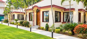 Una hilera de edificios modernos con un estilo arquitectónico uniforme, con amplias ventanas y un jardín bien cuidado con diversas plantas y flores.