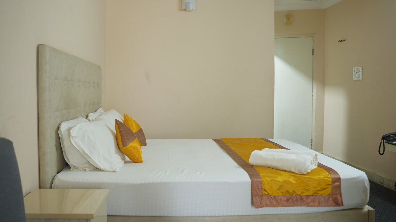 Una camera d'albergo con un letto, un comodino e una porta.