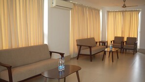 A living room with a sofa, two armchairs, a coffee table, and a ceiling fan. - Hotel Dolphin (Kanthi)