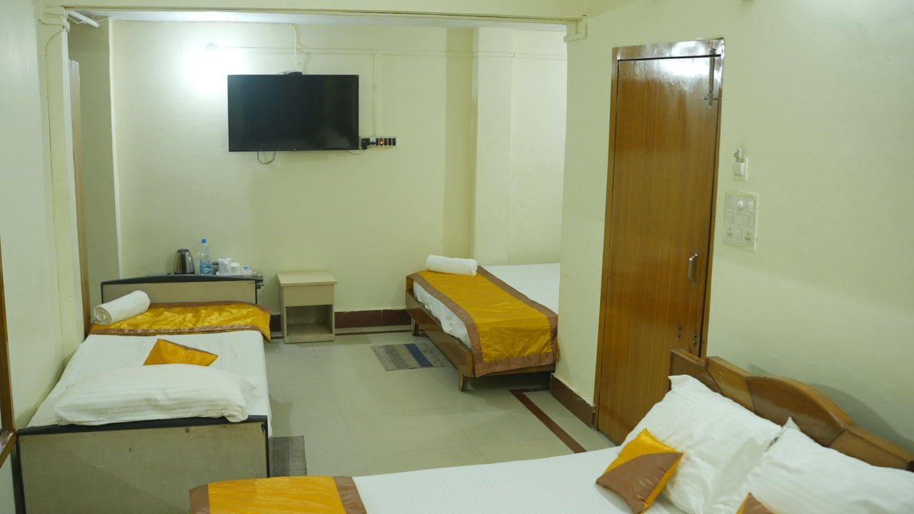 A hotel room with two single beds, a small desk, a television, and a wardrobe.