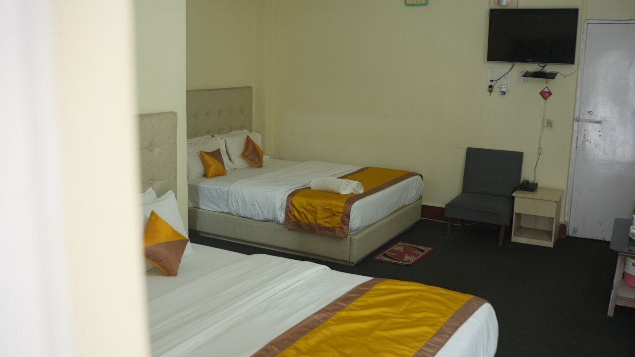 A hotel room with two beds, a TV, a desk, and a chair.