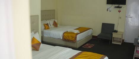 A hotel room with two beds, a TV, a desk, and a chair.