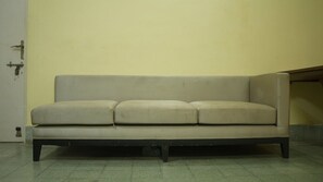 A beige sofa against a yellow wall in a room with a tiled floor. - Hotel Dolphin (Kanthi)