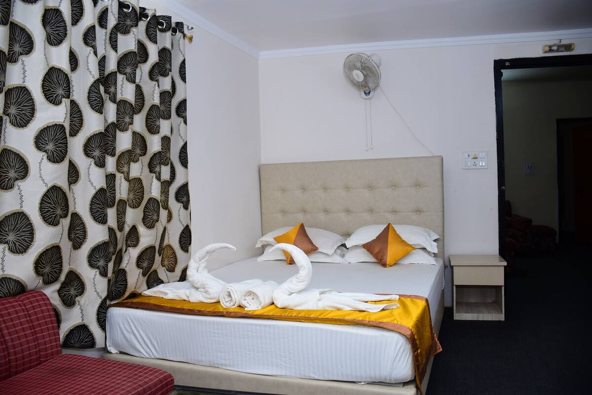 Ein Hotelzimmer mit einem Bett, einem Nachttisch, einem Ventilator und einem roten Sessel.