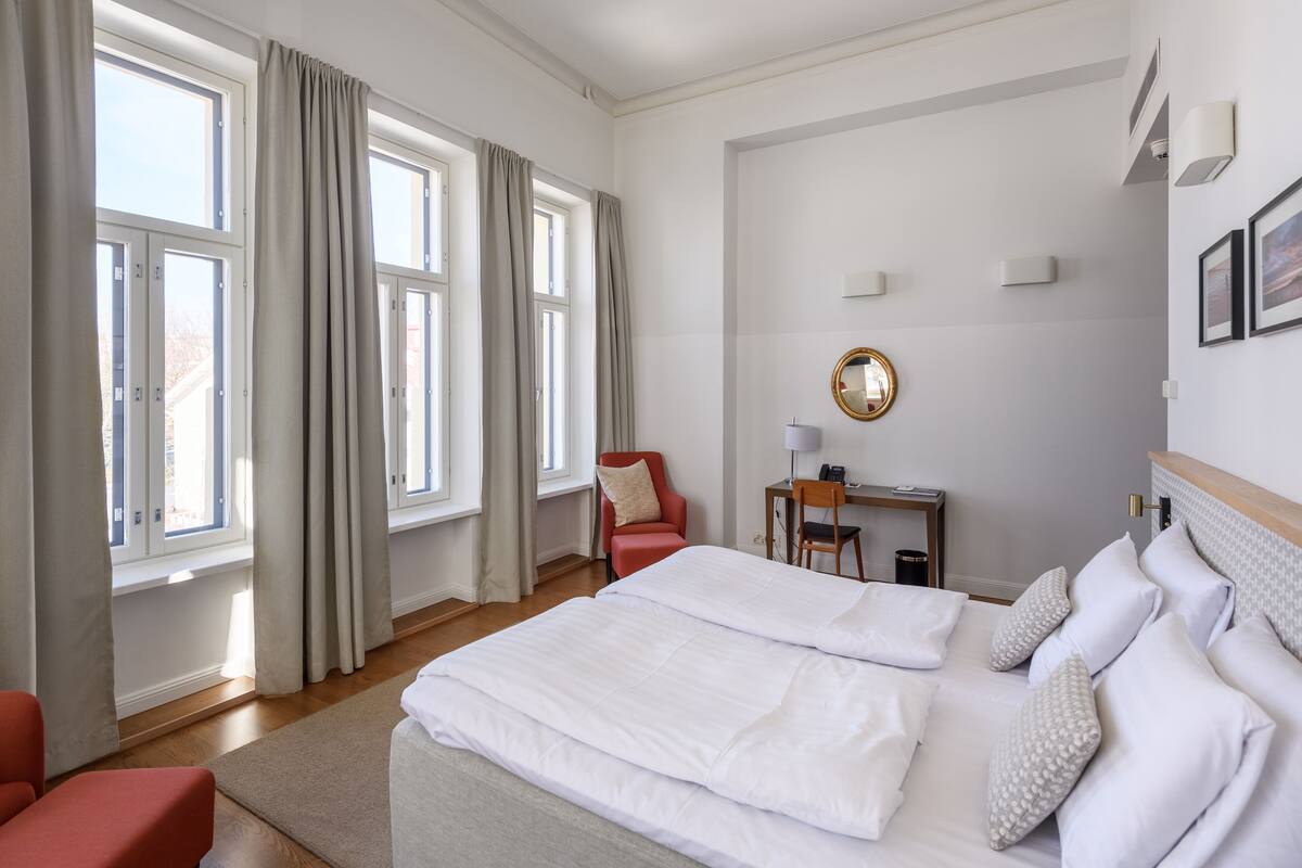 A hotel room with two beds, a desk, and a chair.