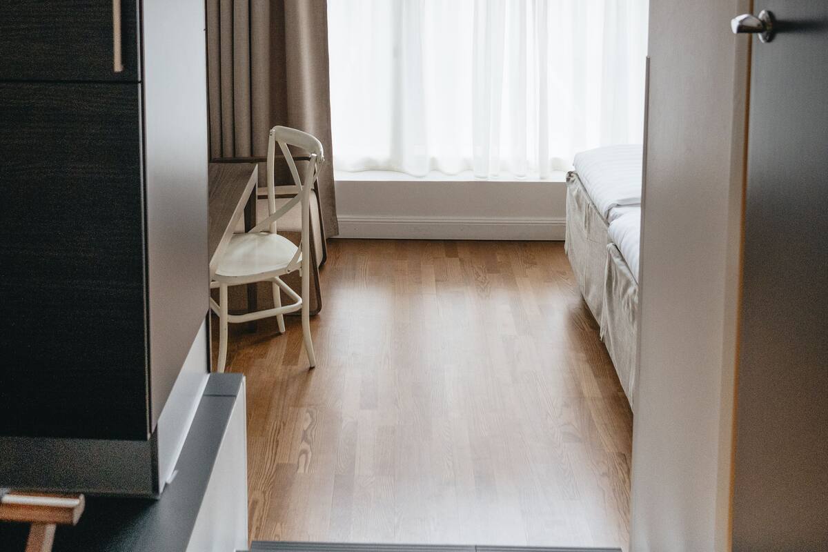 A bedroom with a large window, a bed, a chair, and a desk.