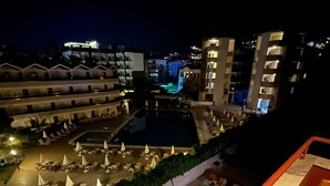 A nighttime view of a hotel with a swimming pool, lounge chairs, and umbrellas. - Maren Beach Apart (Alanya)