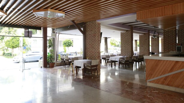 A spacious indoor area with a modern design, featuring a brick column, wooden ceiling, and a counter area. - Maren Beach Apart (Alanya)