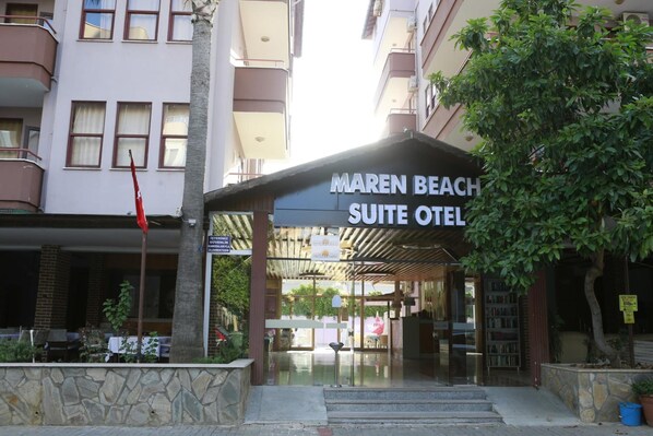 Exterior del Maren Beach Suite Hotel, con entrada cubierta, escaleras de piedra y un cartel.