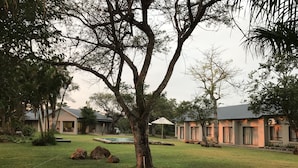 A property with a pool, multiple buildings, and a large tree in the foreground.