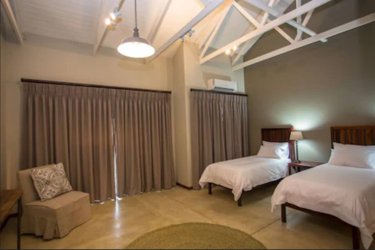 Une chambre d’hôtel avec deux lits, un canapé et une grande fenêtre avec des rideaux.