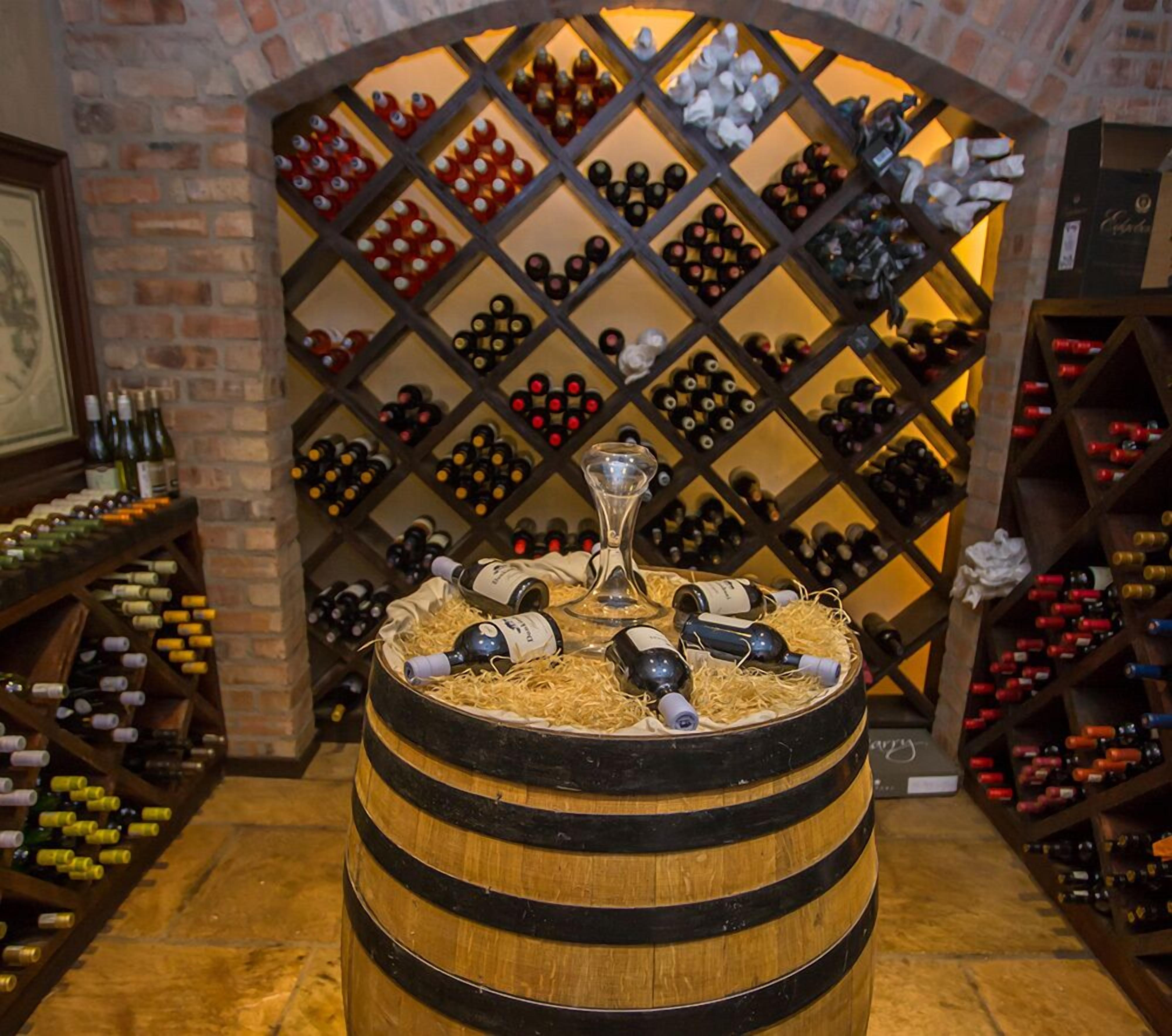 A wine cellar with wooden barrels and a wine rack in the background.