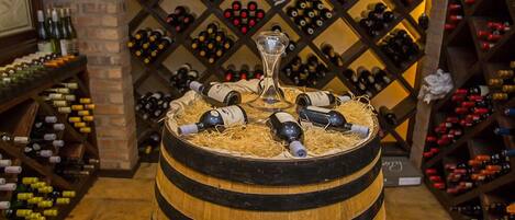 A wine cellar with wooden barrels and a wine rack in the background.