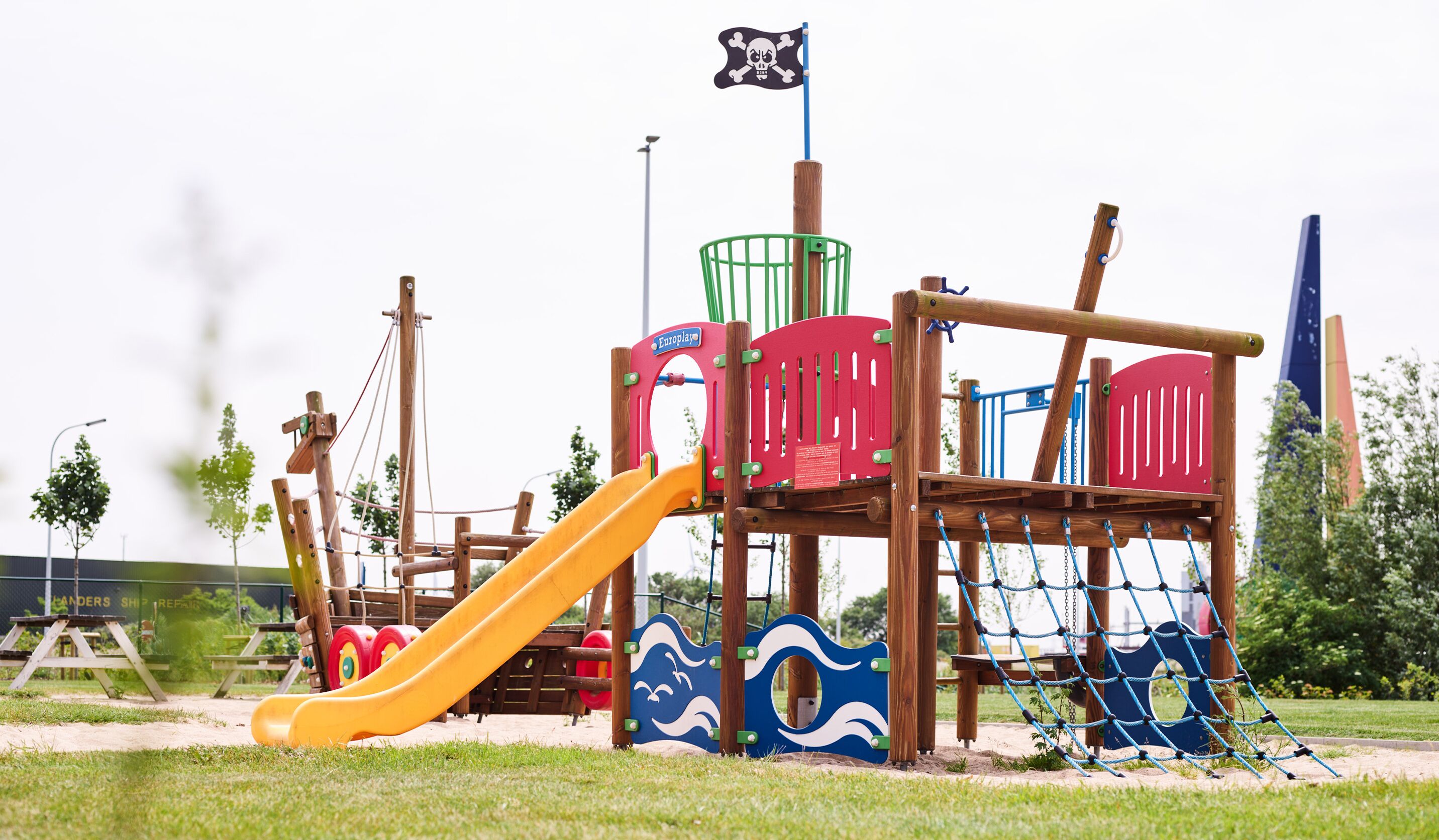 Ein Spielplatz mit Rutsche, Klettergerüsten und einer Piratenflagge.