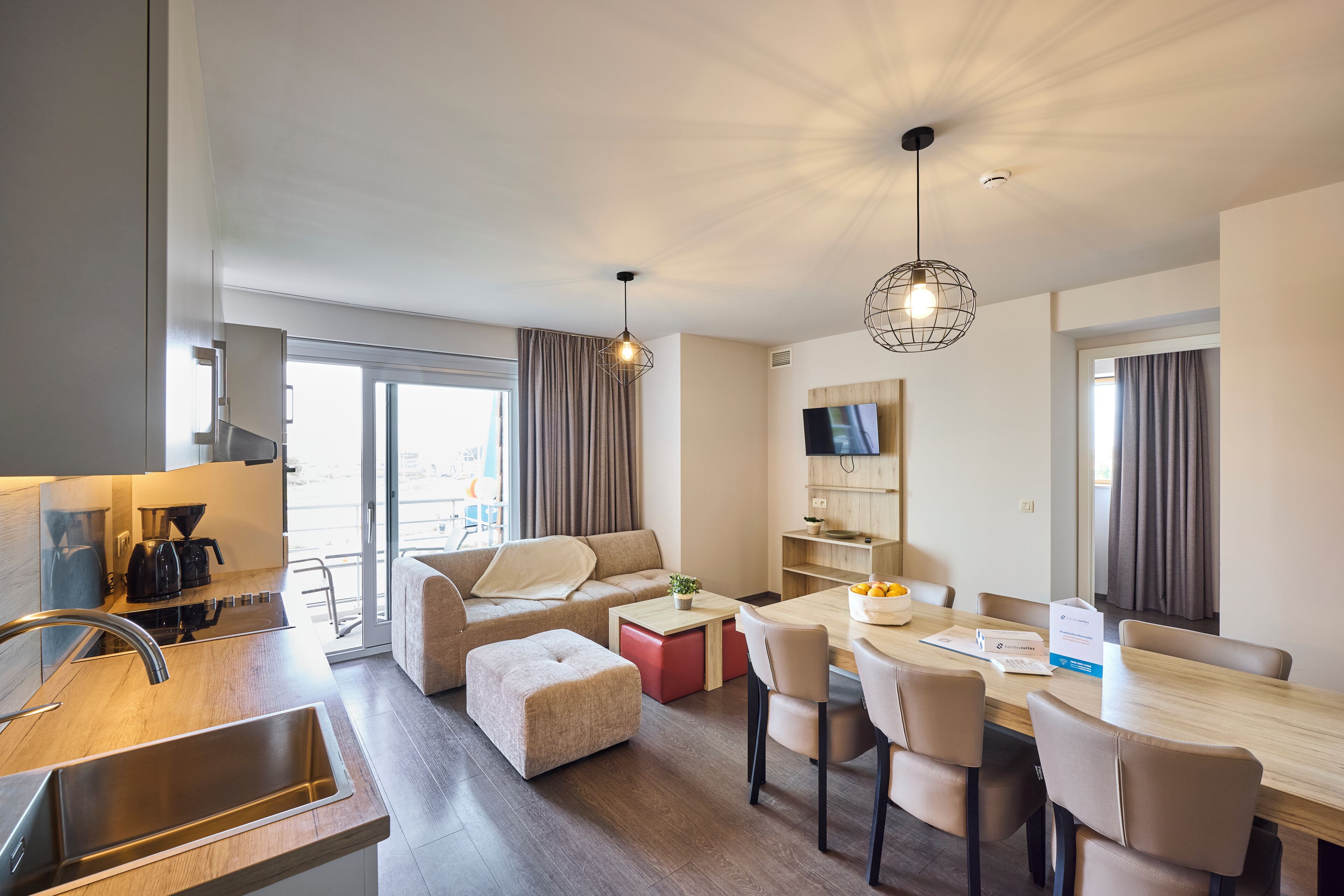 Una habitación de hotel moderna con kitchenette, comedor, sofá y televisión.