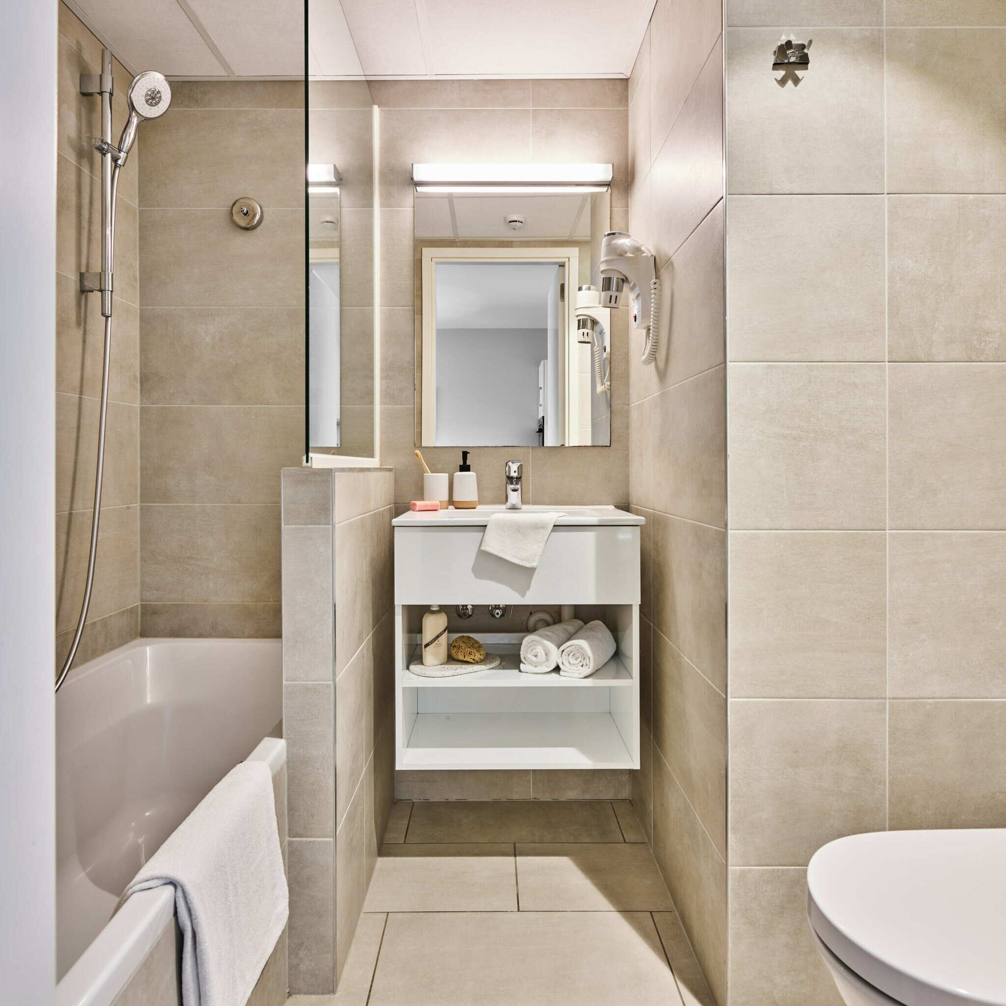 Une salle de bain moderne avec une baignoire, un lavabo avec un miroir et des toilettes.