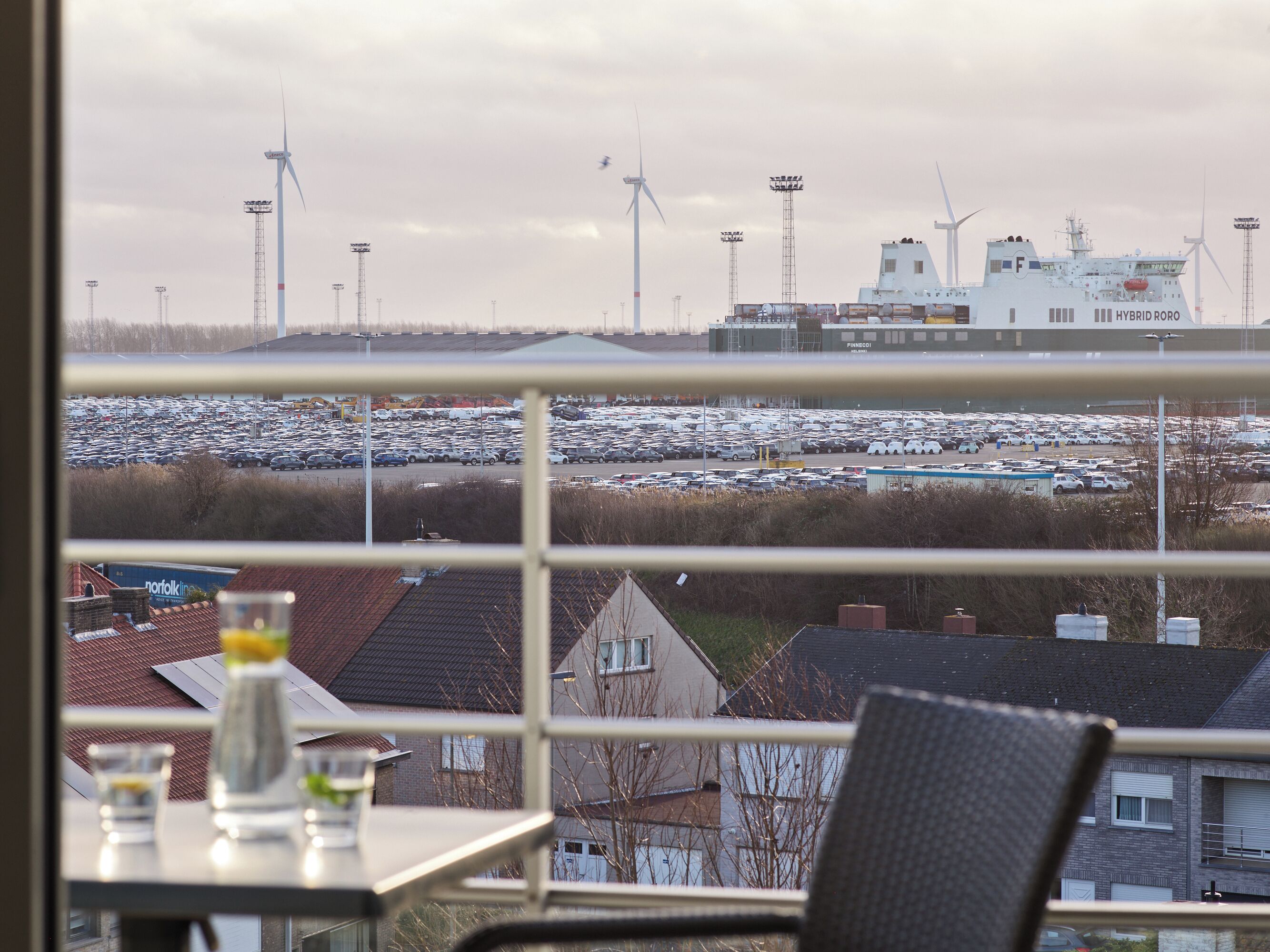 A view from a window overlooking a parking lot and wind turbines in the distance.