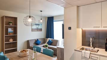 A modern kitchen with a built-in sink, a dining area with a wooden table, and a seating area with a sofa and chairs.