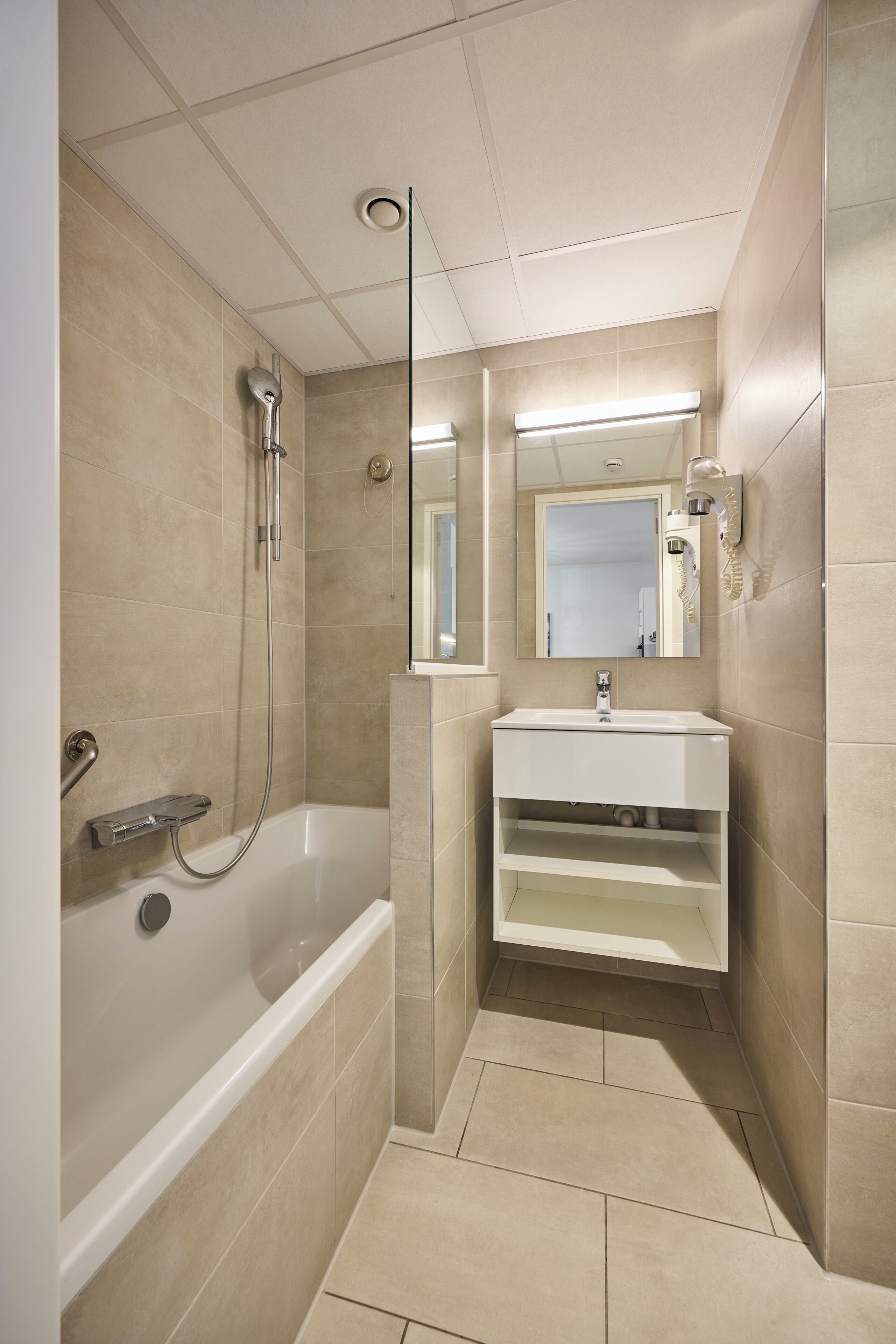 Un baño moderno con bañera, lavamanos, espejo y ducha.