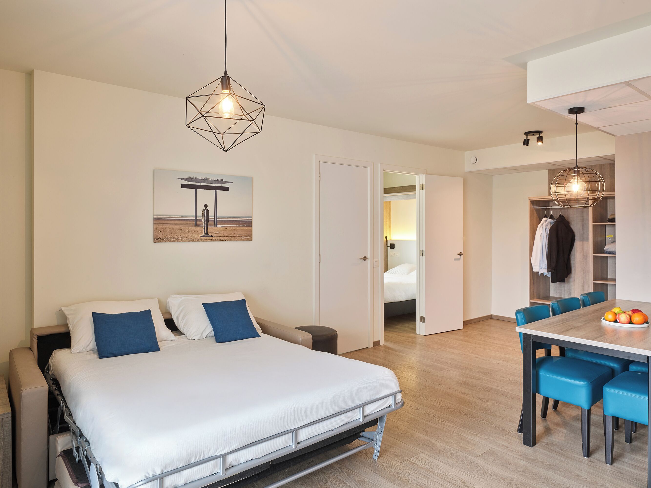 A modern bedroom with a bed, bedside tables, a desk, and a dining area with chairs.