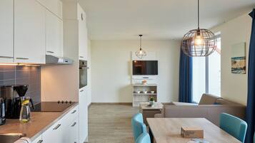 A modern kitchen with white cabinets, a coffee machine, and a dining area with a table and chairs.